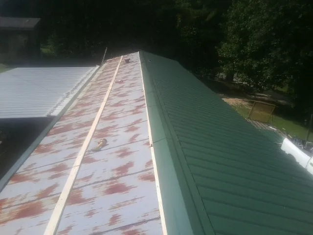 Old rusted panels beside newly installed green metal roofing — Wind Damage Roof Repair by Roofing Brothers in Washingtonville