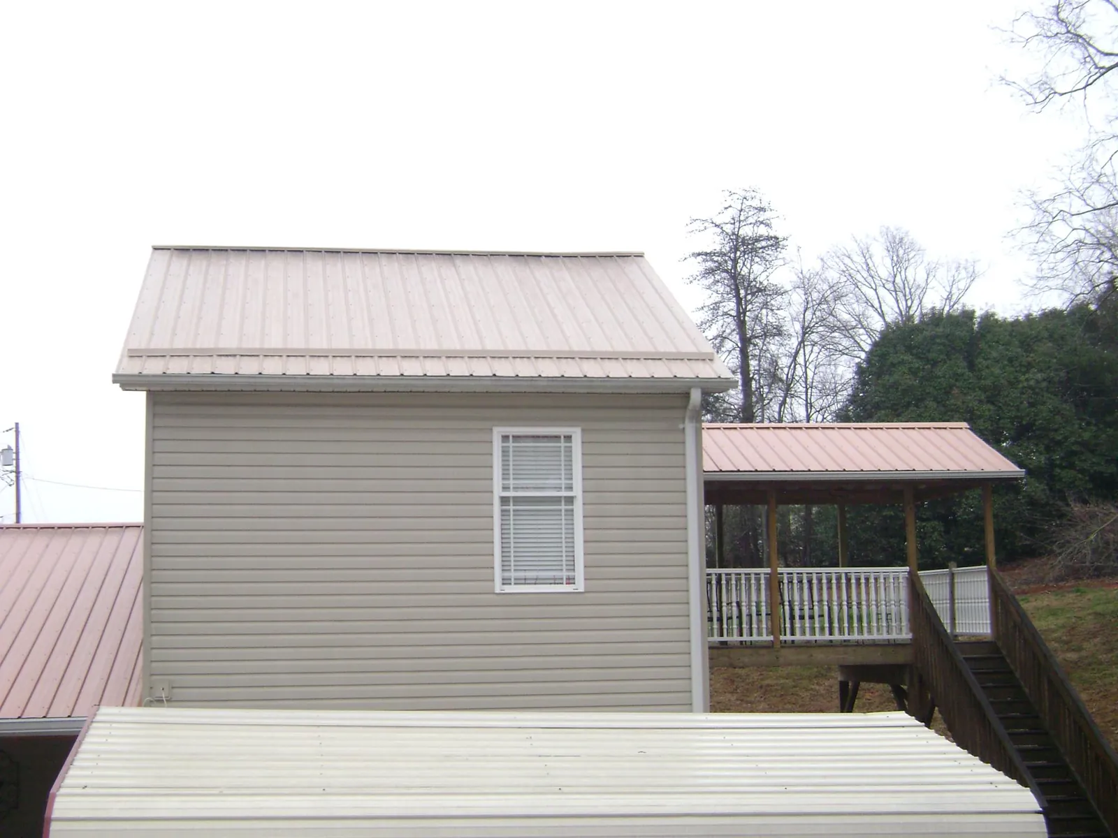 Tan metal roofs on a two story addition and attached porch, from a Roof Replacement job in Washingtonville